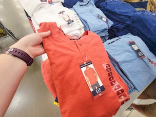 hand holding a burnt orange henley tee