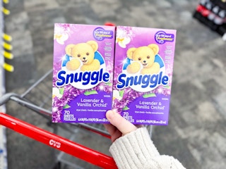 person holding 2 boxes of snuggle dryer sheets over a cvs cart