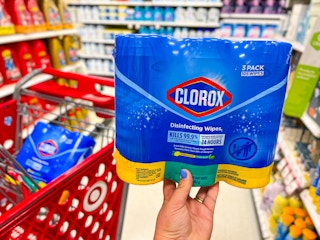 hand holding one 3-pack of Clorox disinfecting wipes next to Target cart