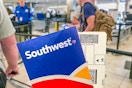 A Southwest airline ticket and envelope being held up while people are standing in line for TSA.