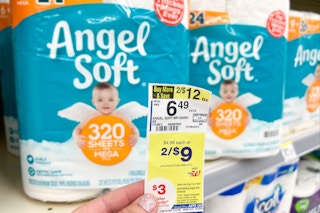 hand holding a walgreens sale tag in front of Angel Soft toilet paper packs on a shelf