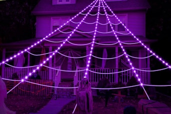 purple spider web lights glowing in front of house
