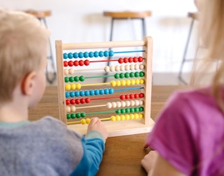 two kids playing with an abacus