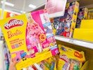hand holding a play-doh barbie fashion show playset in front of a shelf