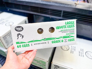 hand holding a box of great value 60 count eggs in walmart aisle