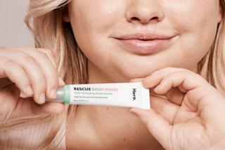 a woman holding a tube of skin cream