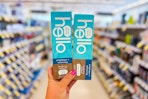 person holding 2 hello toothpastes in an aisle