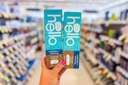 person holding 2 hello toothpastes in an aisle