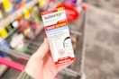 person holding sudafed nasal spray over a cart