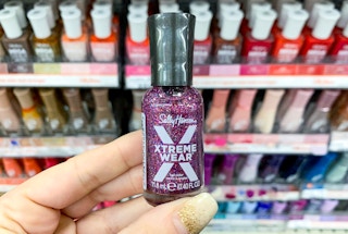 hand holding a bottle of sally hansen xtreme wear purple sparkle nail polish