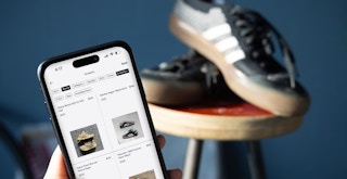 Someone looking at sneakers on the GOAT app with sneakers in the background