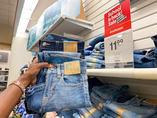 someone holding a pair of kids jeans next to a sale sign
