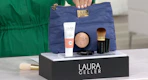 Laura Geller makeup next to a cosmetics bag on a display