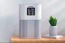 VEWIOR Air Purifiers for Home sitting on an end table next to a plant.