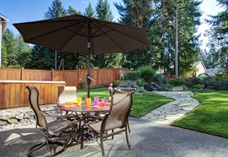 A brown patio umbrella near patio furniture outside.