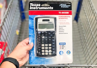 hand holdnig texas instruments scientific calculator above walmart cart