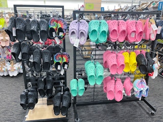 A display of hanging Crocs classic clogs at a shoe store.