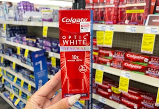 hand holding colgate premium toothpaste in aisle