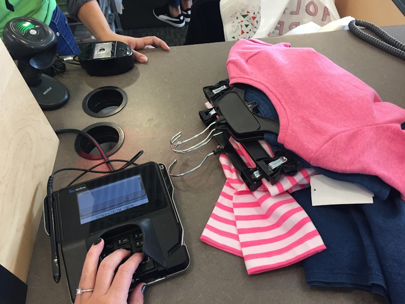 A woman hand on credit card machine returning clothes in Nordstrom Rack