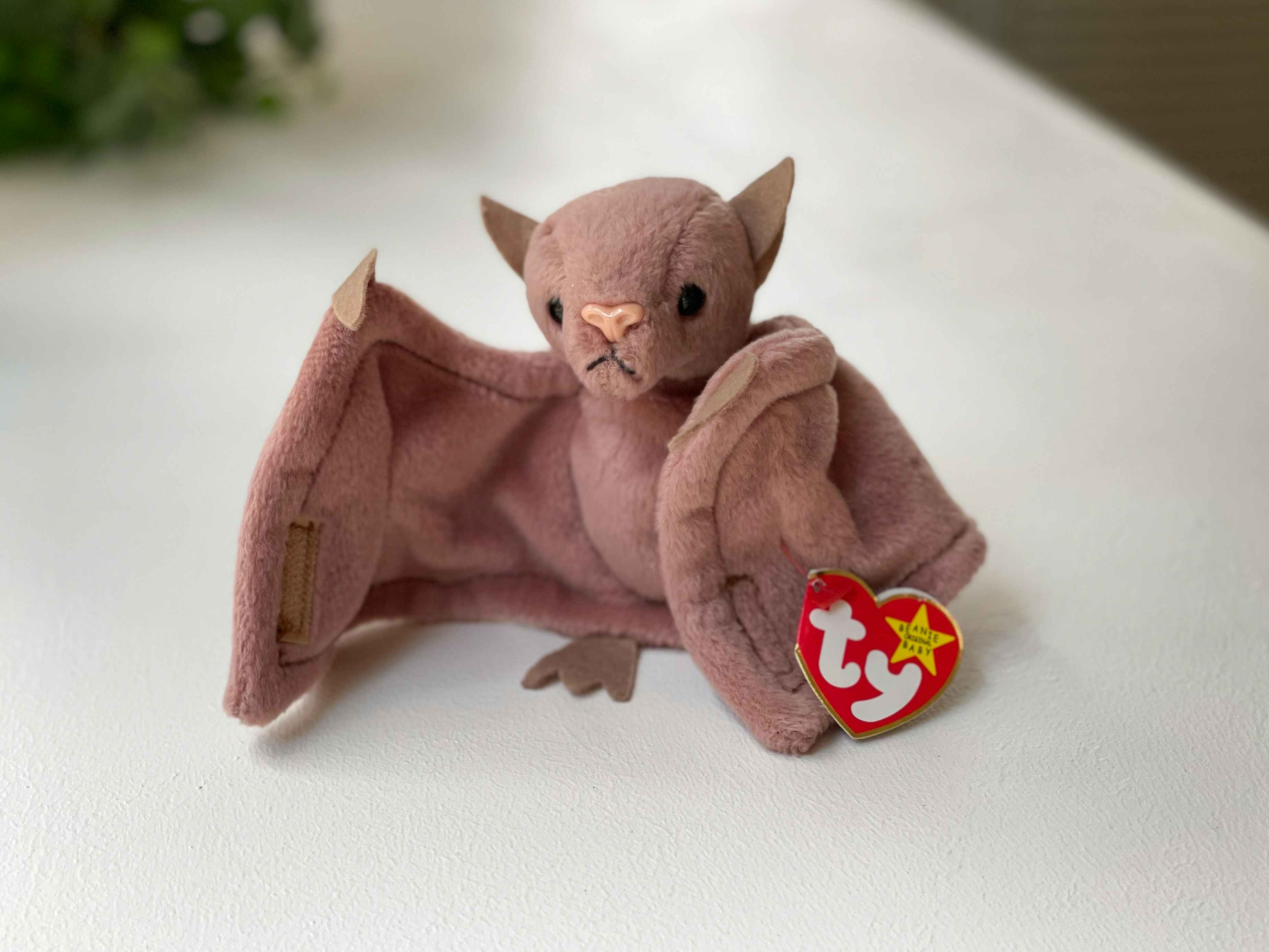 A Batty the Bat beanie baby sitting on a white table.