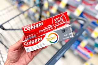 hand holding two toothpastes in front of walgreens shopping cart in store aisle