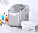 a grey ice maker next to a container of ice and drinks