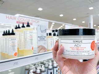 Woman holding hair product in front of display