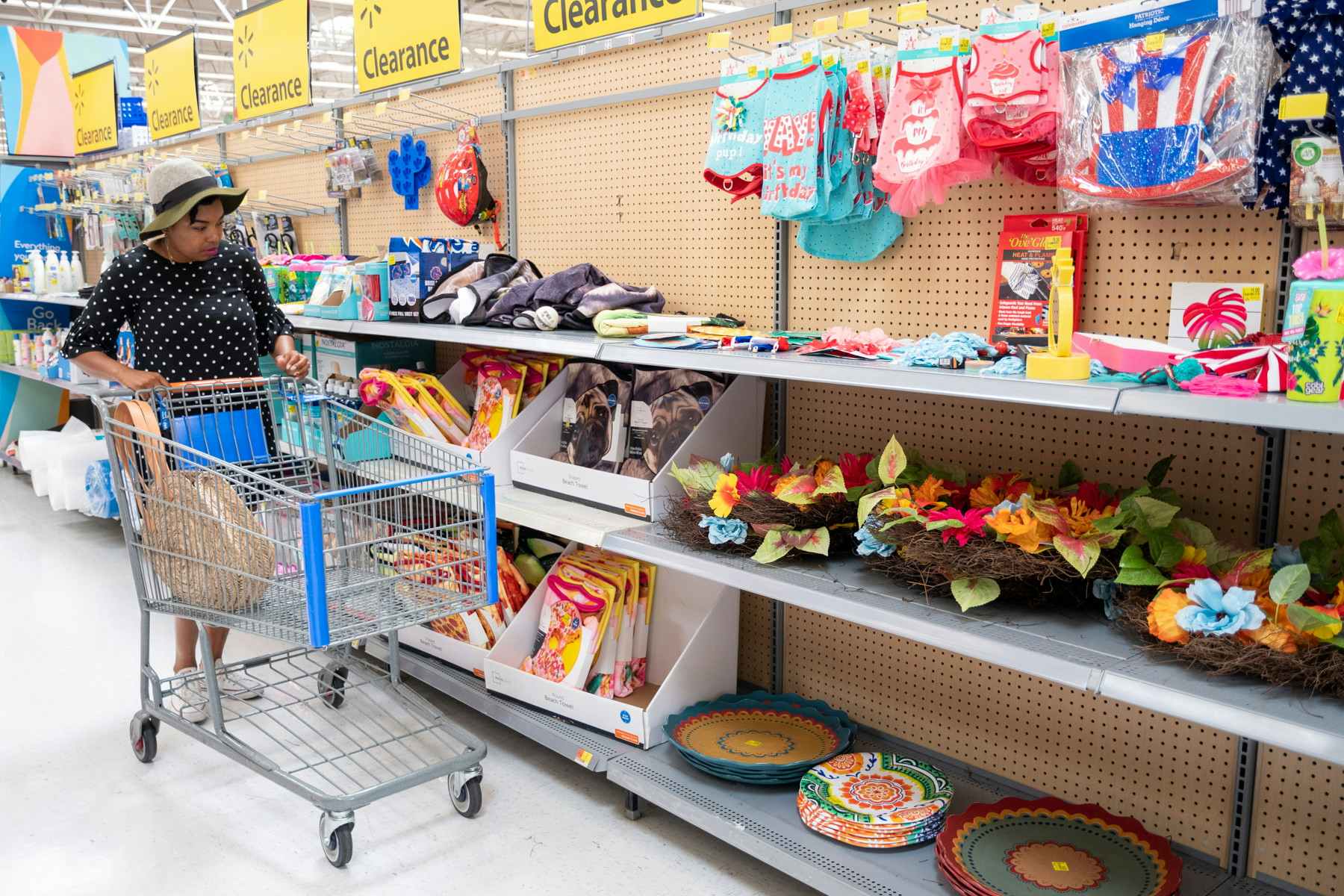A womand pushing a shopping cart down a clearance aisle in a Walmart store.