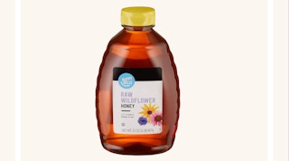 A bottle of honey on a tan background