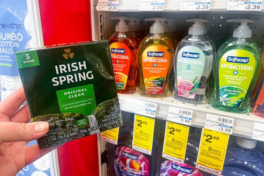 person holding irish spring bar soap next to softsoap hand soap