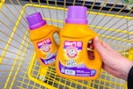 hand lifting an arm & hammer laundry detergent above a cart