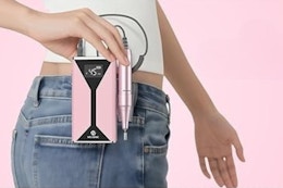 Woman holding a cordless nail file machine.