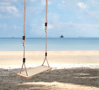a wooden swing on a beach