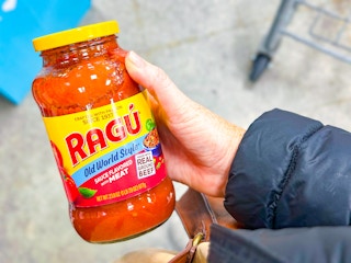 hand holding a jar of ragu pasta sauce