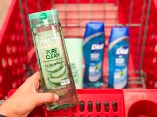 hand holding Garnier shampoo in front of Target shopping cart