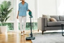 woman using Shark stick vacuum on carpet in living room