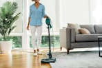 woman using Shark stick vacuum on carpet in living room