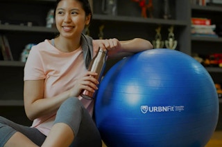 A woman leaning on her yoga ball.