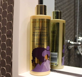 Gold shampoo bottle next to a mirror