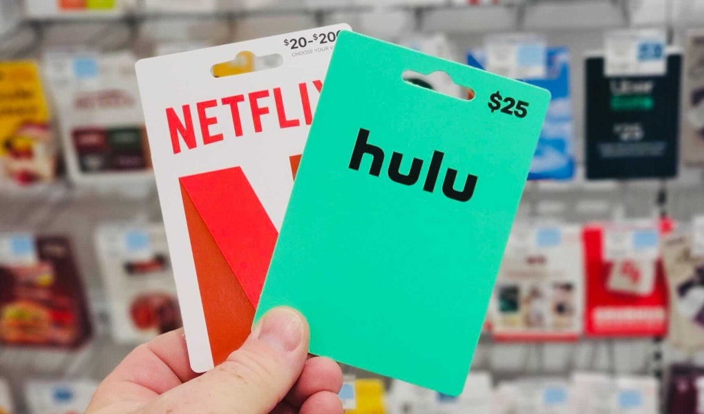 someone holding hulu and netflix gift cards