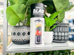 Ninja Blast Portable Blender sitting next to some green plants on a shelf at kohl's