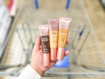 hand holding three loreal lumi foundations over walmart cart