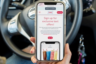 A person holding a phone with the Sonic text message screen open on it.