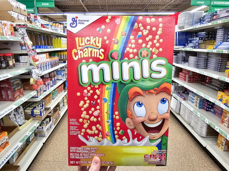 person holding a box of lucky charms minis cereal
