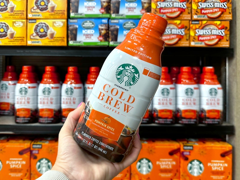 hand holding bottle of starbucks pumpkin spice cold brew near other fall products in jewel osco