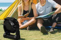 a woman and man near a tent and camping fan