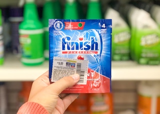 hand holding small pack of Finish dish detergent and coupon