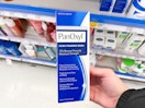 a hand holding a blue and white box in a store aisle 