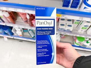 a hand holding a blue and white box in a store aisle 