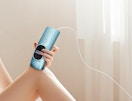 a person using a teal laser hair remover on their legs